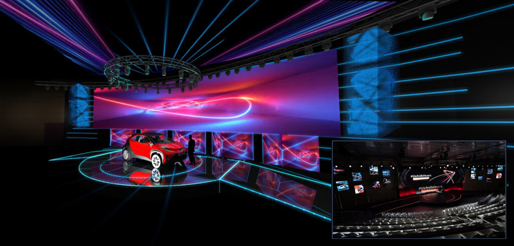 Toyota-Auditorium (5) Rendering di uno stage immersivo per evento automotive con pedana circolare e vettura al centro, circondata da pannelli LED dinamici, luci laser e schermo panoramico ad alta risoluzione con grafiche futuristiche. L’ambiente è progettato per una presentazione spettacolare di nuovi modelli auto, combinando tecnologia scenografica e design innovativo.