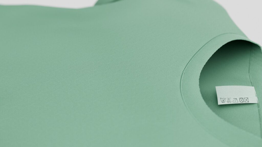 closeoop_01 Dettaglio di una maglietta verde in tessuto tecnico con etichetta di lavaggio visibile, realizzata come rendering 3D ad alta definizione per illustrare la texture e la qualità del materiale.