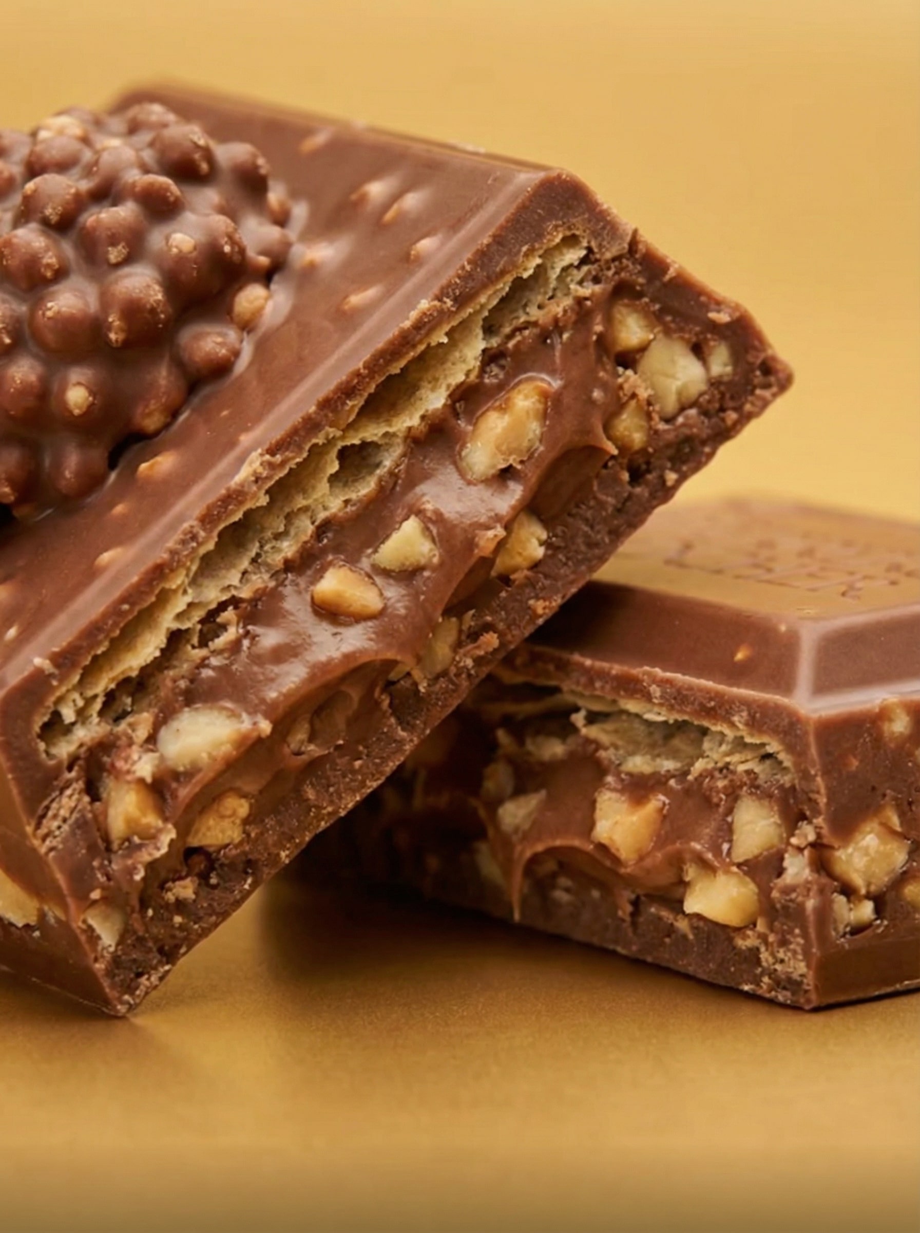 Dettaglio macro sezione trasversale tavoletta Ferrero Rocher che mostra il ripieno cremoso e la granella di nocciole interna.