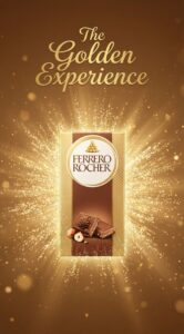 Packaging verticale tavoletta Ferrero Rocher ambientato su sfondo particellare dorato con claim The Golden Experience.