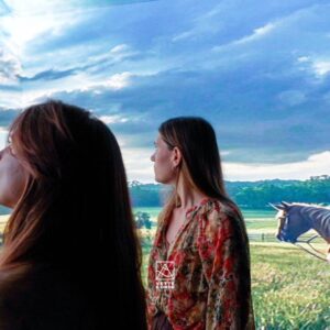 Installazione immersiva Vette e Onde: visitatrice osserva una proiezione di tramonto su barca a vela creata con AI generativa6