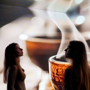 Installazione immersiva Vette e Onde: visitatrice osserva una proiezione di tramonto su barca a vela creata con AI generativa5