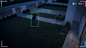 Sistema di sicurezza che rileva un intruso, figura di ladro in movimento in area residenziale notturna, evidenziazione automatica con box di tracking, overlay di rilevamento AI, atmosfera tesa ma pulita, stile pubblicità tecnologia sicurezza.